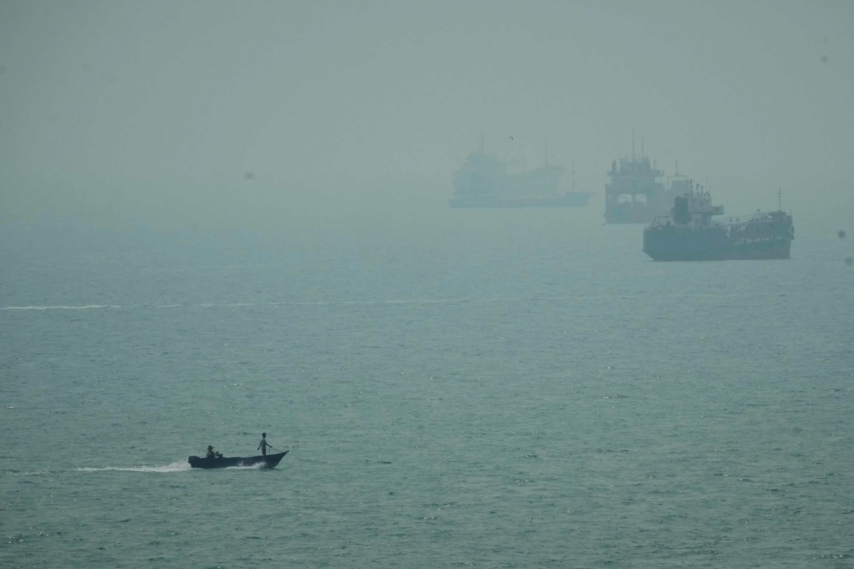 A motorboat travels past commercial vessels anchored amid haze in the Strait of Hormuz off Bandar Abbas, Iran, Monday, Sept. 7, 2026. (AP Photo/Vahid Salemi)